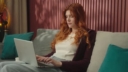 Woman Working on Laptop on Couch at Home