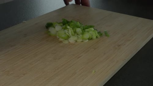 Minced Scallions Being Chopped on a Cutting Board