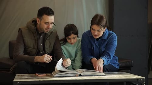 A Husband Wife and Their Daughter Look Through a Catalog While Sitting in a Furniture Showroom