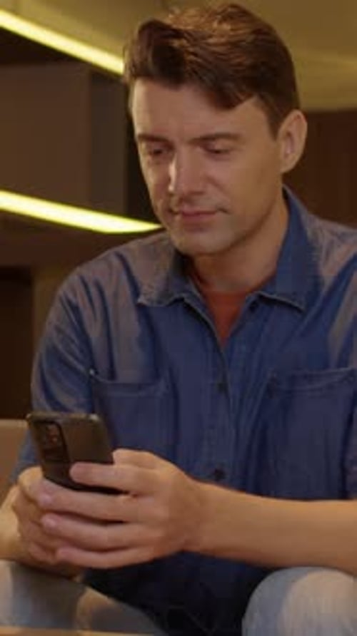 Man Smiling and Texting on Smartphone Indoors