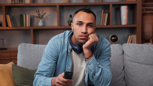 Bored Young Adult Sitting on Couch with Remote