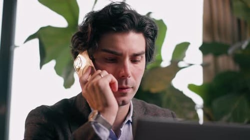 a serious man a businessman works at a laptop in the office communicates with colleagues smartphone
