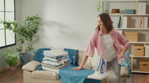 Woman Dancing while Ironing Clothes at Home