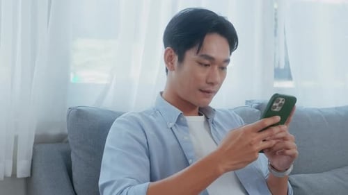 Man Using Phone, Relaxing Indoors on Sofa