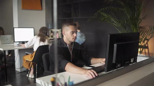 Young Businessman Discussing with Colleague Over Desktop Pc in Office