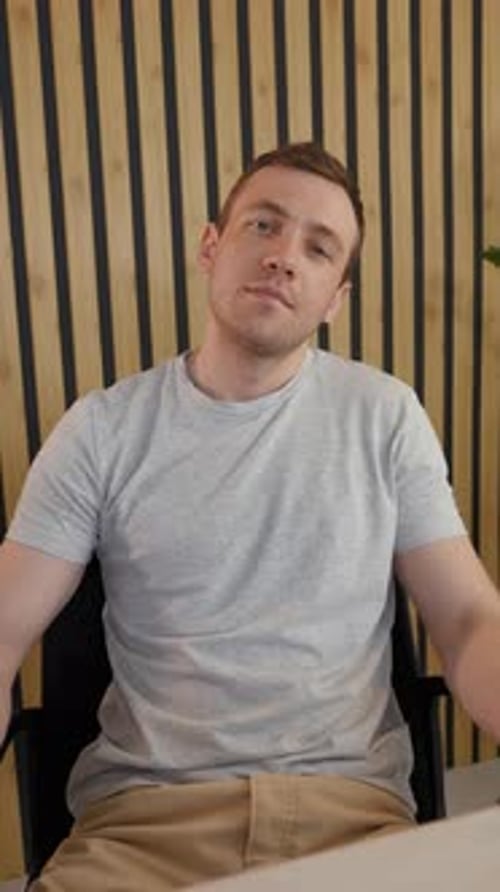 Young Man Sitting at Desk Smiling at Camera