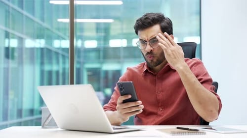 Man Frustrated While Using Mobile Phone in Office