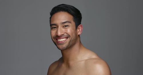 Face, funny and Asian man with beauty, skincare and dermatology on a grey studio background
