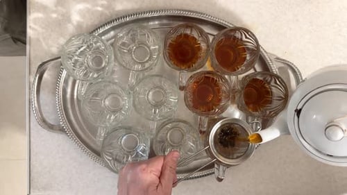 Serviço de chá turco em um café com jardim com garçom entregando chá quente em copos de vidro em bandeja de metal captu