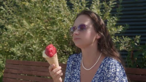 Woman Enjoys Ice Cream Cone on Sunny Park Bench
