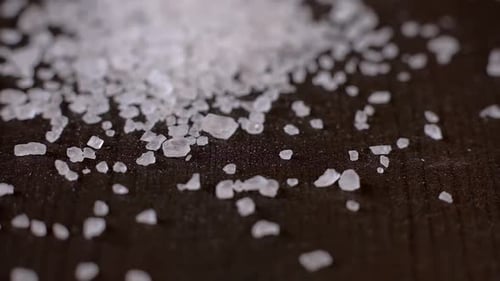 Crystals of White Sea Salt Fall on the Wooden Table