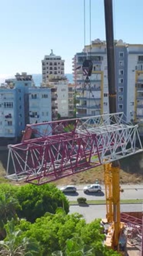 Vertical Video Aerial Footage Of Workers Handling Large Crane Parts On A Construction Site With