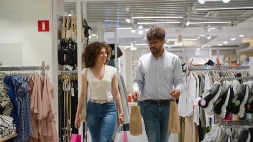 Happy Couple Walking Through Clothing Store Holding Shopping Bags