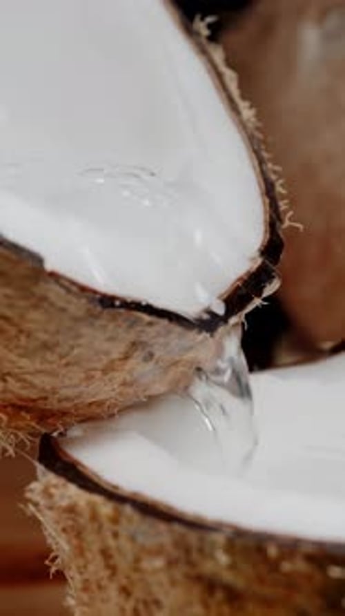 Clear Liquid Pours from Cracked Coconut Halves