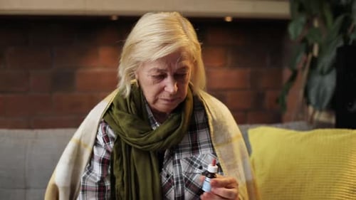 Senior Woman Taking Medicine on Couch at Home