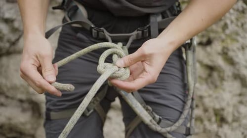 Alpinista amarra corda em volta dos quadris e pernas, seguro de equipamento para evitar situações perigosas
