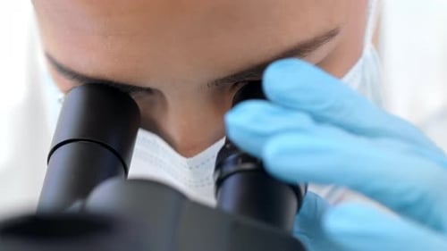 Woman in Lab Coat Using Microscope