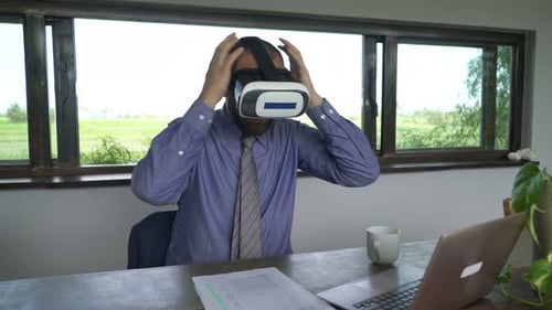 Young businessman wearing vr goggles looks around at table in modern apartment