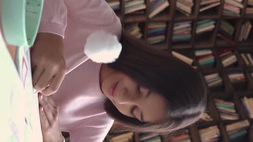 Happy indian teen schoolgirl smiles studying at desk doing homework at home in India