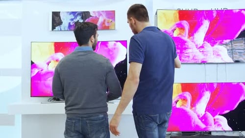 In the Electronics Store Professional Consultant Shows Latest 4K UHD TV's to a Young Man, They Disc