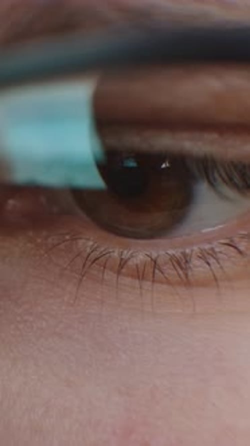 Nahaufnahme eines menschlichen Auges, das digitales Licht reflektiert und die Hautstruktur der Wimpern zeigt und