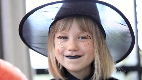 Child Wearing Witch Hat and Black Lipstick Smiling