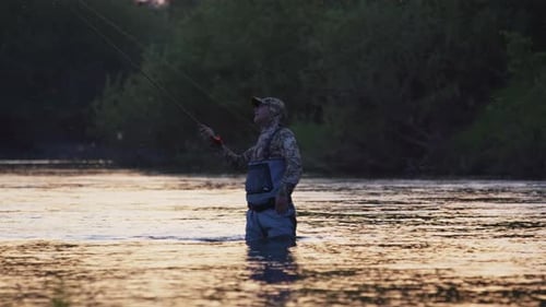 Fly fishing. Fisherman casts fly on the river at sunset. Caucasian amateur angler fishing on the riv