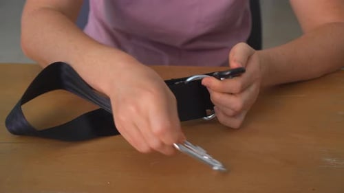 Mulher sentada à mesa conectando mosquetões de metal com som nítido e montando mãos de perto