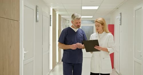 Doctor and Nurse Briefing Medical Report Two Doctors in a Hospital Corridor