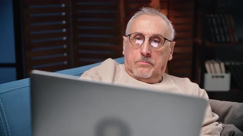 Senior Man Relaxing with Laptop on Sofa Indoors
