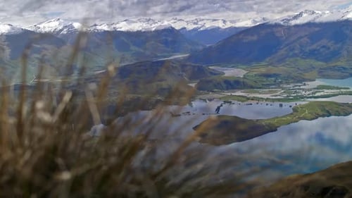 A beautiful green valley with mountains above a lake on a bright sunny day on a grassy hill, driftin