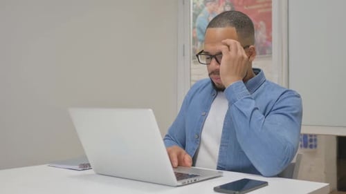 Man Working on Laptop, Rubbing Eyes