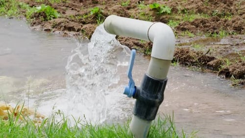 bore water coming from pipe to use in crop field lands, day time, stable shot, 4k.