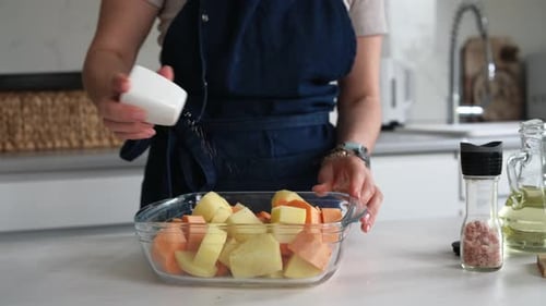 Woman Salting Diced Vegetables in Kitchen for Cooking
