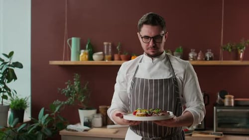 Man Holding Plate of Food in Kitchen Setting