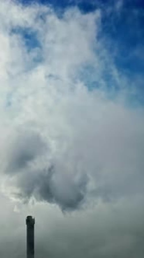 Industrial Smokestack Against Blue Sky With Clouds