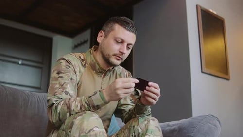 Man in Camouflage Uniform Sitting and Looking at Card