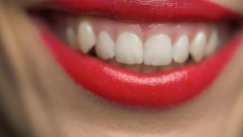 Nahaufnahme der weichen roten Lippen einer jungen lächelnden Frau mit perfekten Zähnen