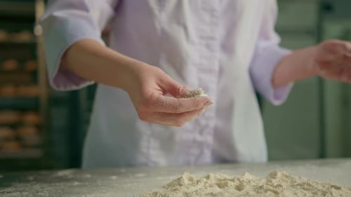 professional chef throws flour on table stirs it before preparing bread pastry in bakery