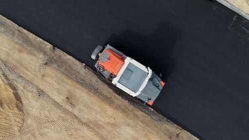 Road roller pressing a new strip of asphalt along a highway
