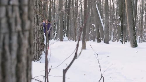 Young Man and Woman Running and Talking in Winter Forest
