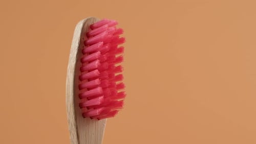 Bamboo toothbrush rotate on an orange background.