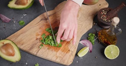Woman Cutting and Chopping Cilantro or Parsley Greens on a Wooden Cutting Board at Domestic Kitchen