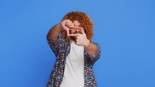 Man with Curls Frames with Fingers, Thumbs Up