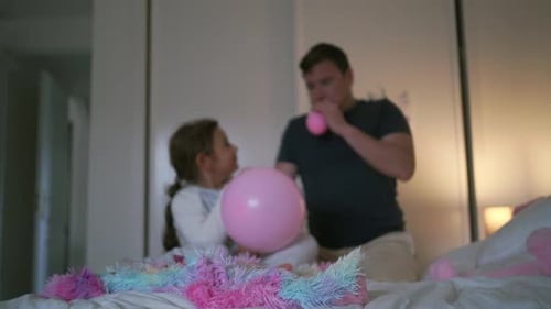 Man and Girl Blowing Up Pink Balloons
