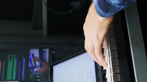 Hands playing on midi keyboard piano at recording studio. Vertical video