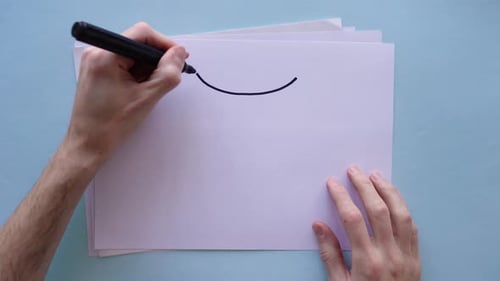 Person drawing Gemini zodiac sign on sheet of paper. Top view.