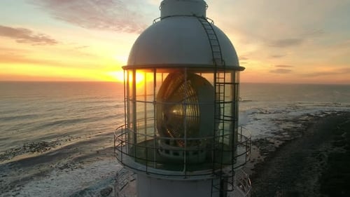 Aerial, drone and lighthouse at the ocean on a sunset sky at night or morning sunrise
