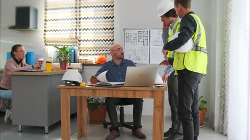 Una pareja caucásica observa la reunión de un contratista con un cliente sentado en el hogar, chaleco de alta visibilidad