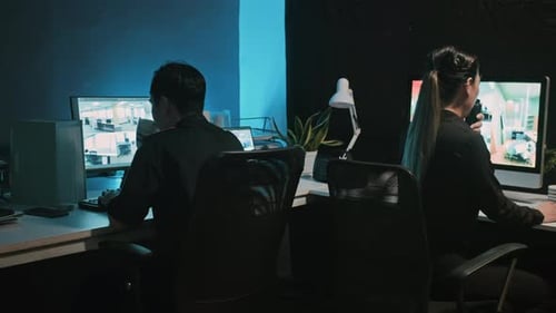 Security Guards Monitoring Surveillance Footage in Dark Office